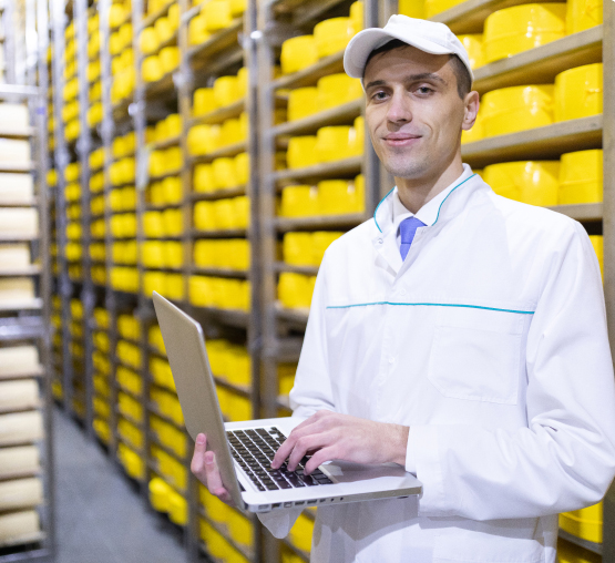 smiling man in a white coat, with a laptop in front of cheese